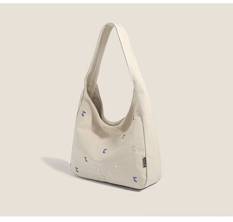 Side view of khaki embroidered canvas hobo shoulder bag with all-over colorful stitch details