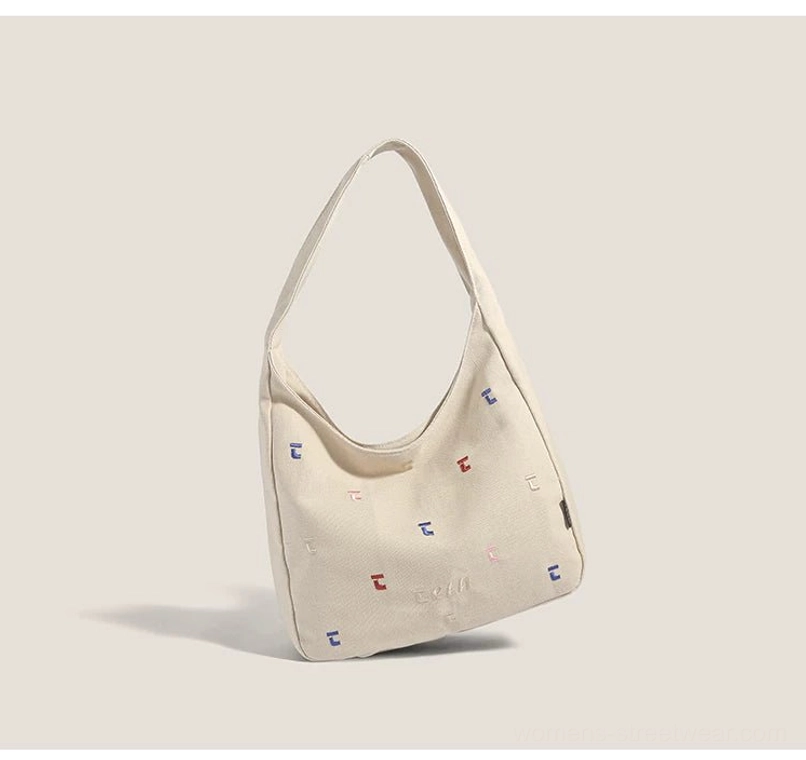 Khaki canvas hobo shoulder bag with colorful confetti stitch embroidery and curved underarm silhouette