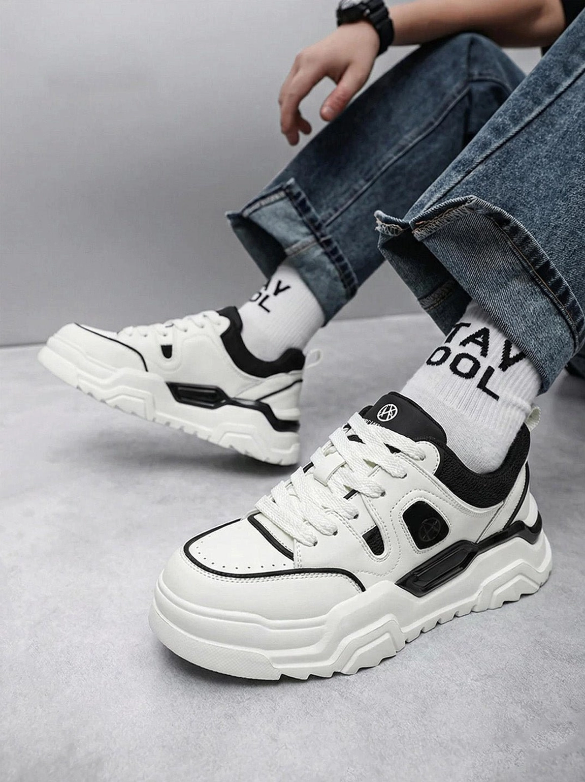 Top view of black and white cutout platform sneakers worn with rolled jeans and crew socks