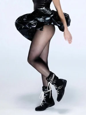Model wearing black contrast lace-up buckled mid-calf combat boots with a glossy black mini dress and sheer tights