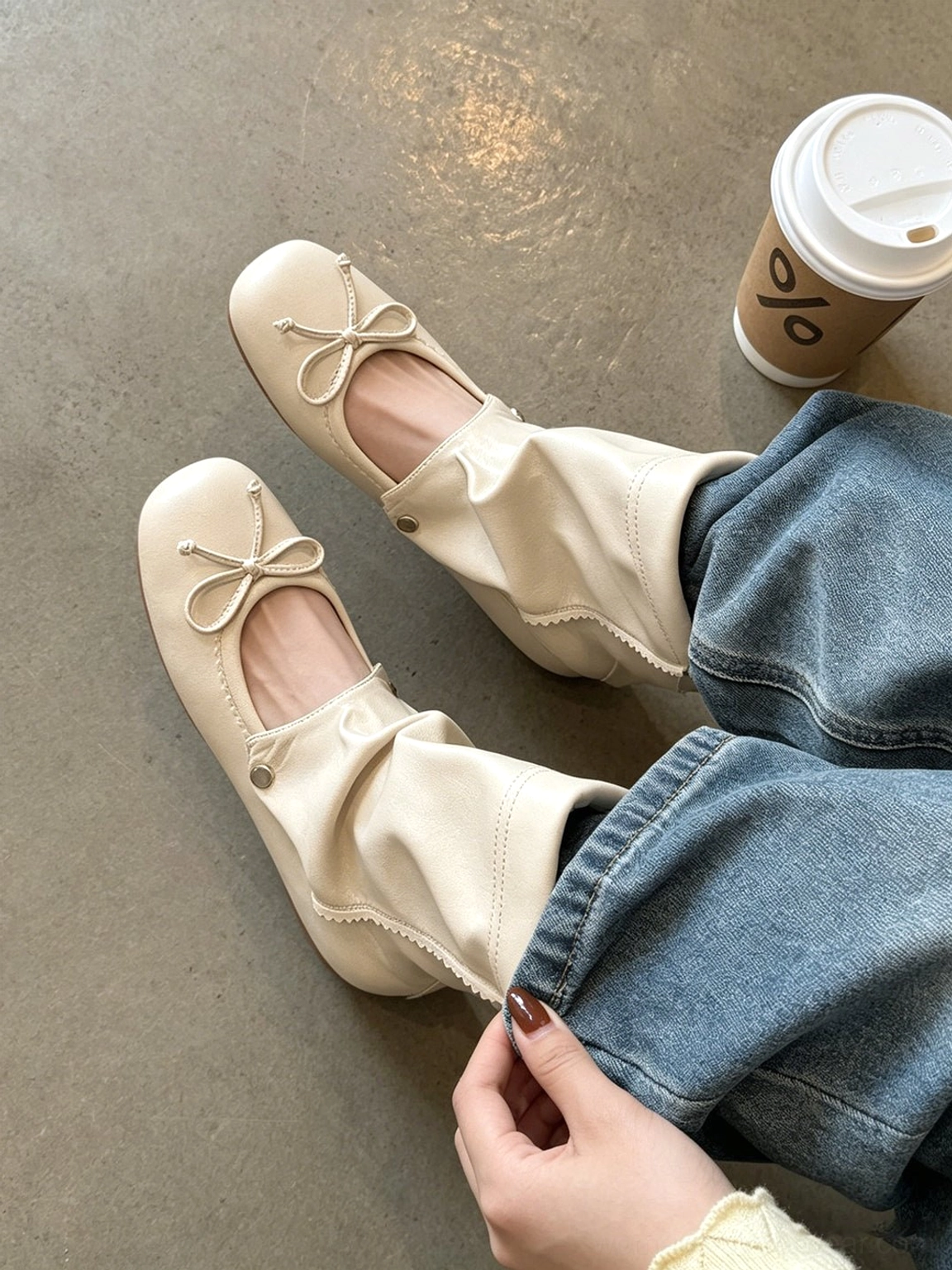 Beige slouchy bow-wrap sandal boots worn with blue denim jeans in a casual coffee streetwear look