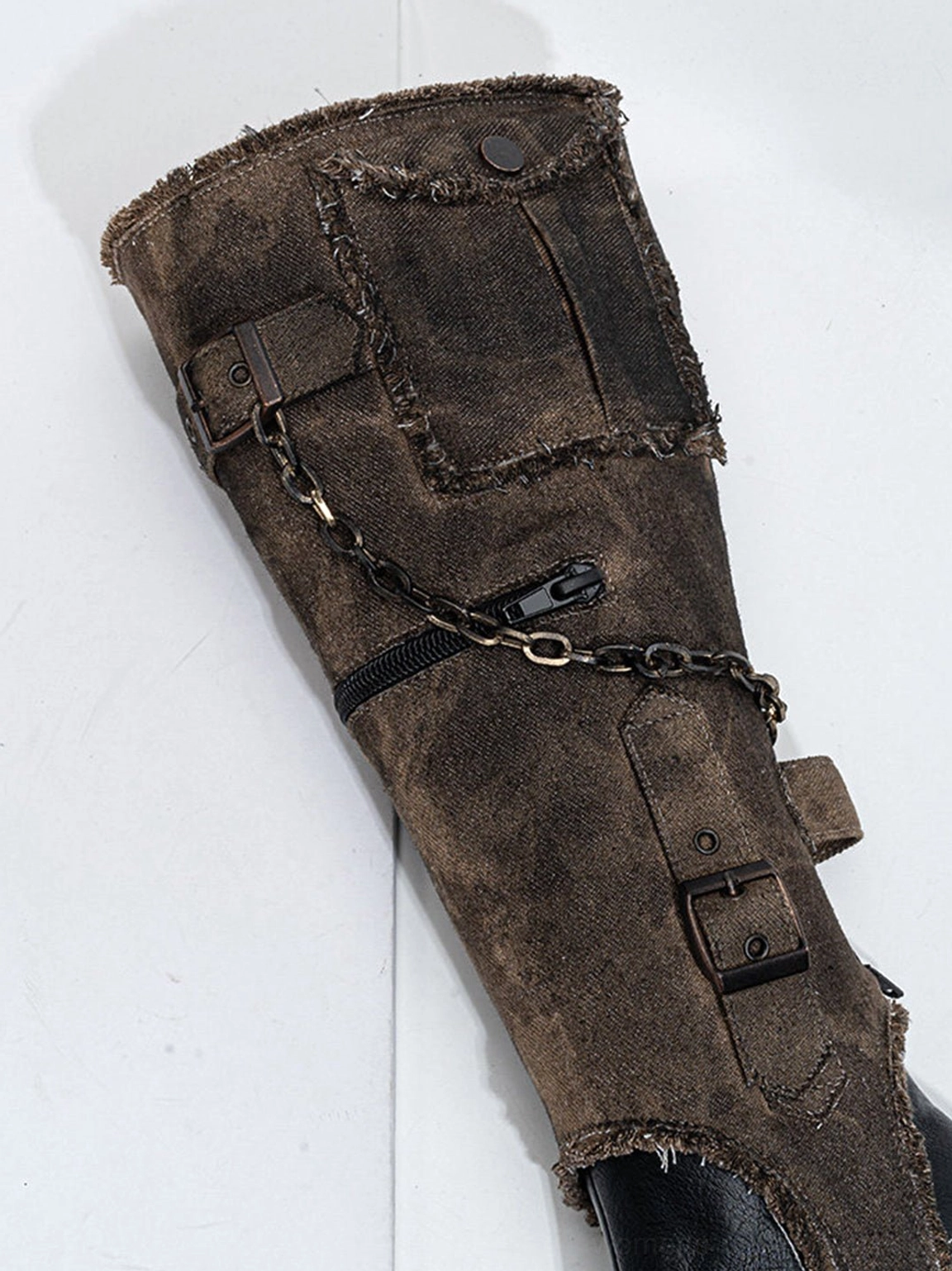 Close-up of detachable distressed fabric boot shaft with frayed trim, chain, buckles, zipper, and patch pocket