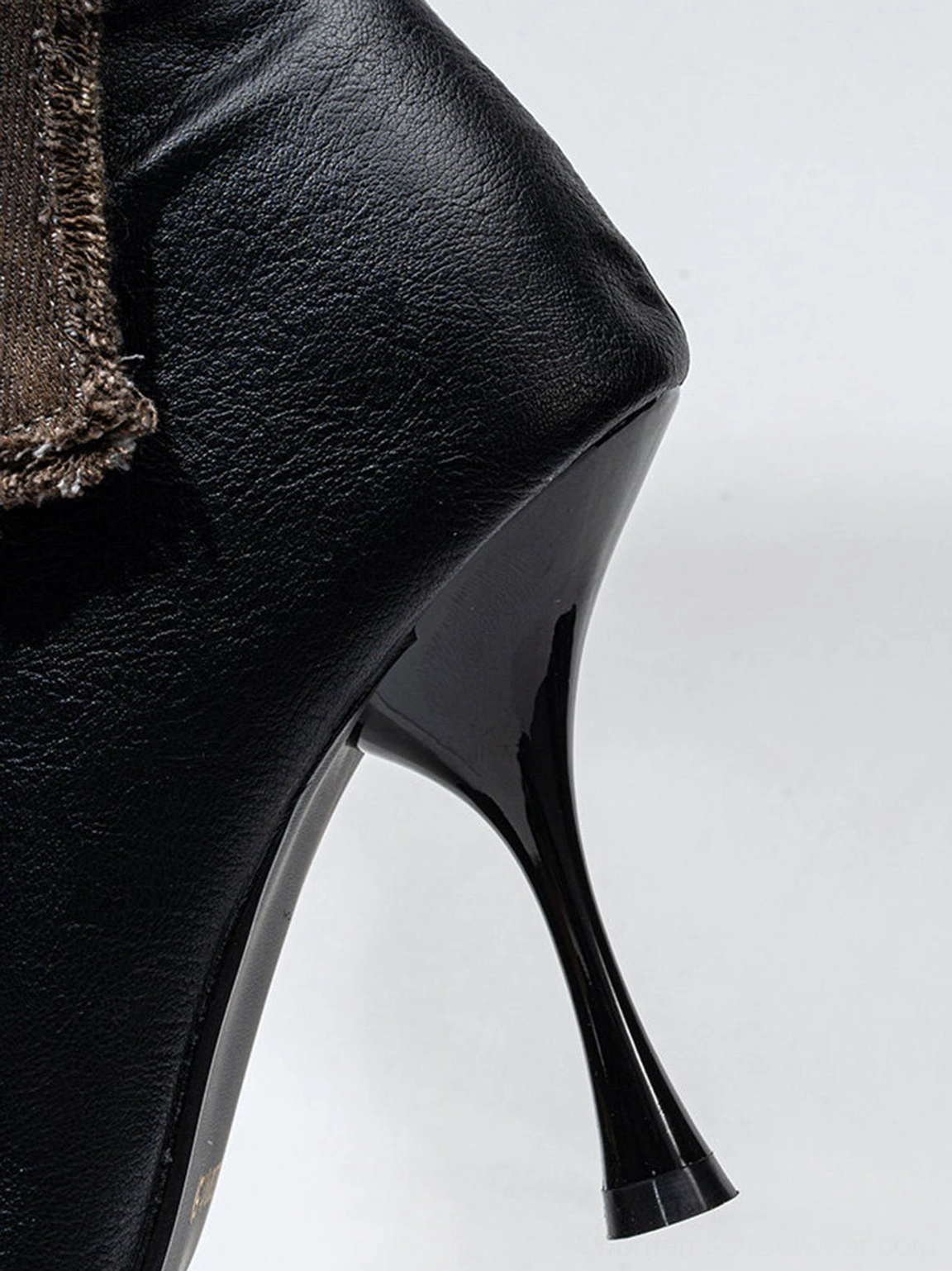 Side close-up of smooth black stiletto boot heel with distressed fabric trim and pointed silhouette