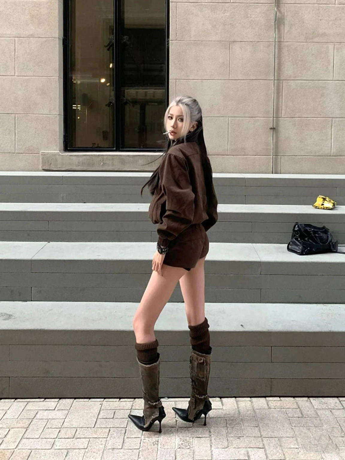 Brown distressed shaft black pointed stiletto boots styled with a cropped jacket and shorts outfit