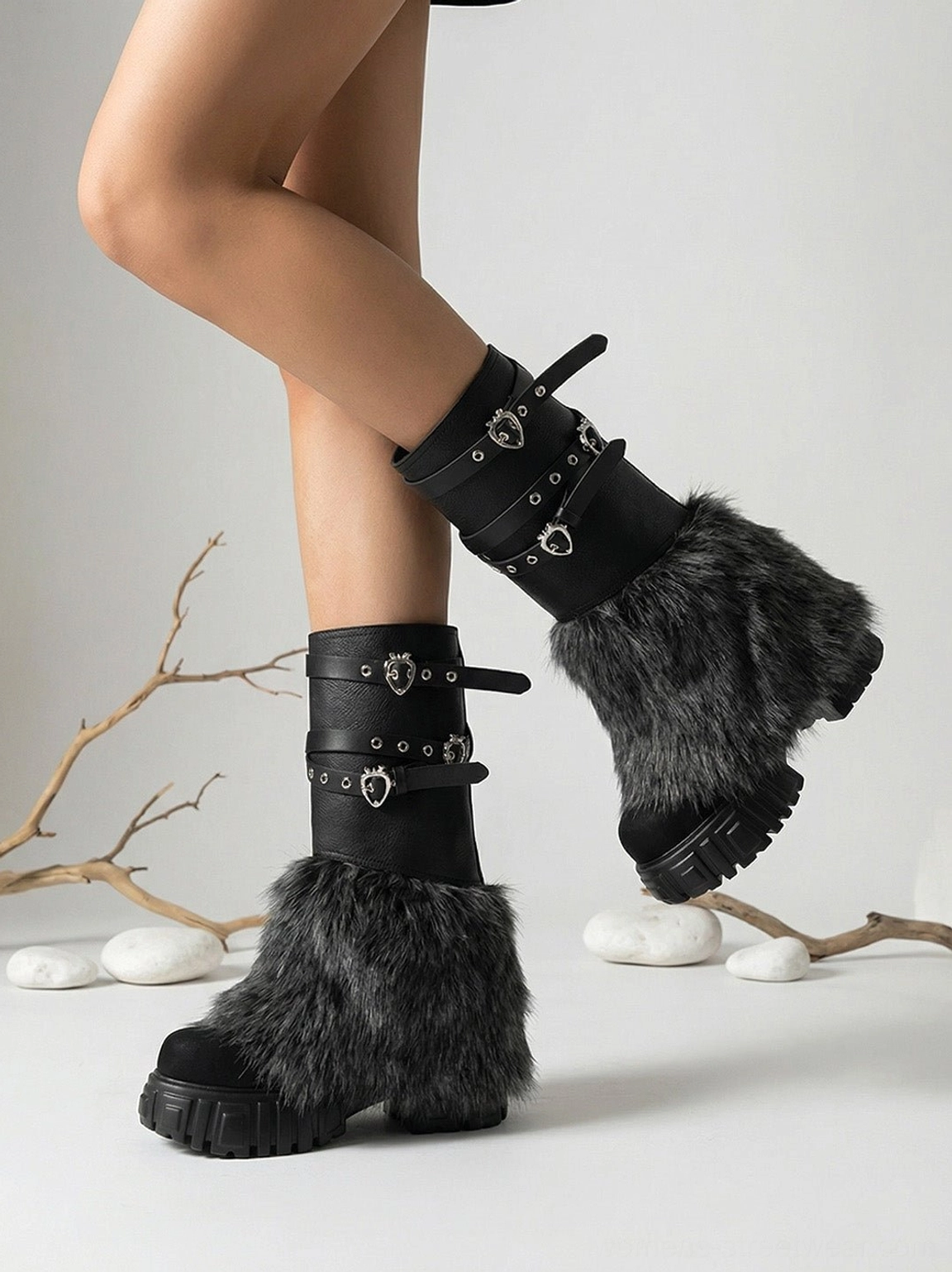 Close side three-quarter view of faux fur platform boots showing metal buckle straps, grey furry trim and chunky lug platform