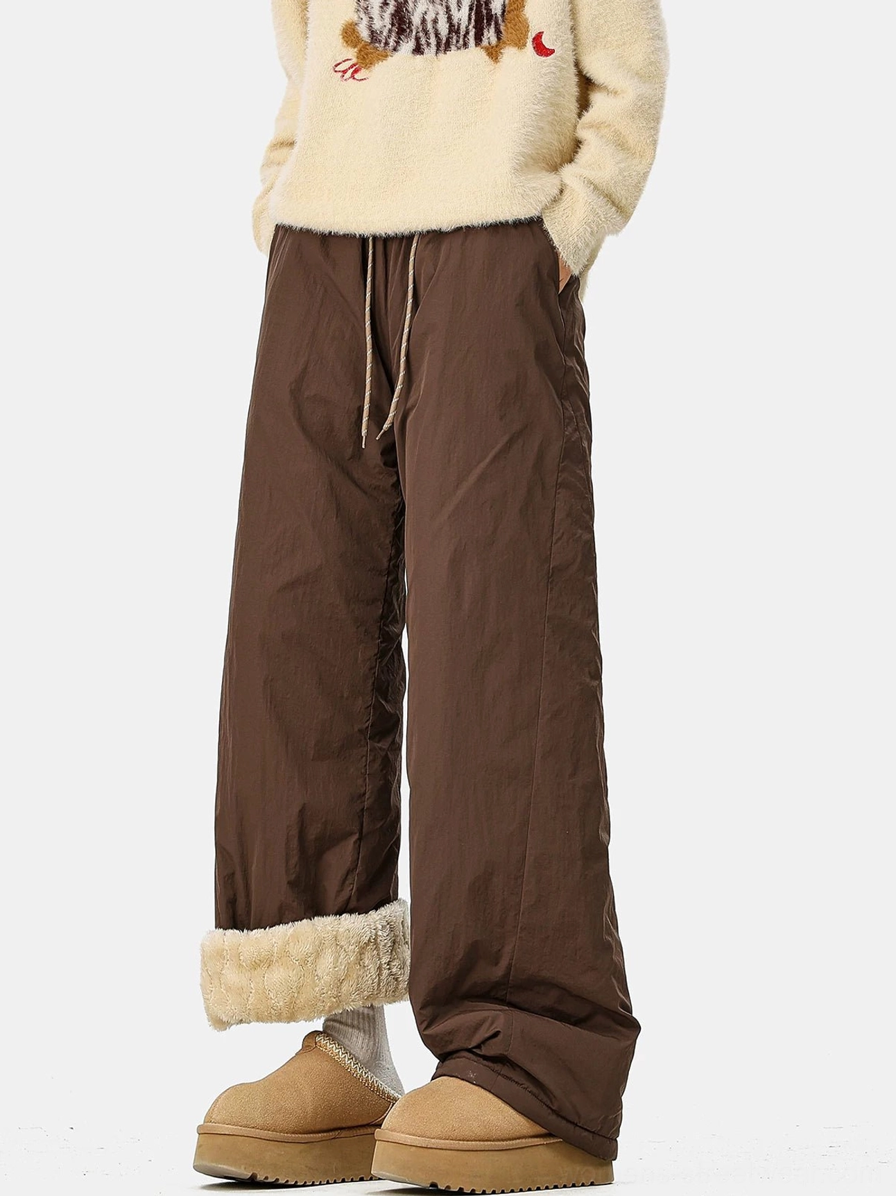 Dark brown convertible fleece-lined wide-leg streetwear pants with rolled shearling cuffs styled with a fuzzy sweater and platform snow boots
