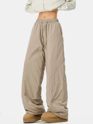 Light khaki convertible wide-leg streetwear pants with crinkled polyester shell, drawstring waist, cropped sweatshirt, and snow boots