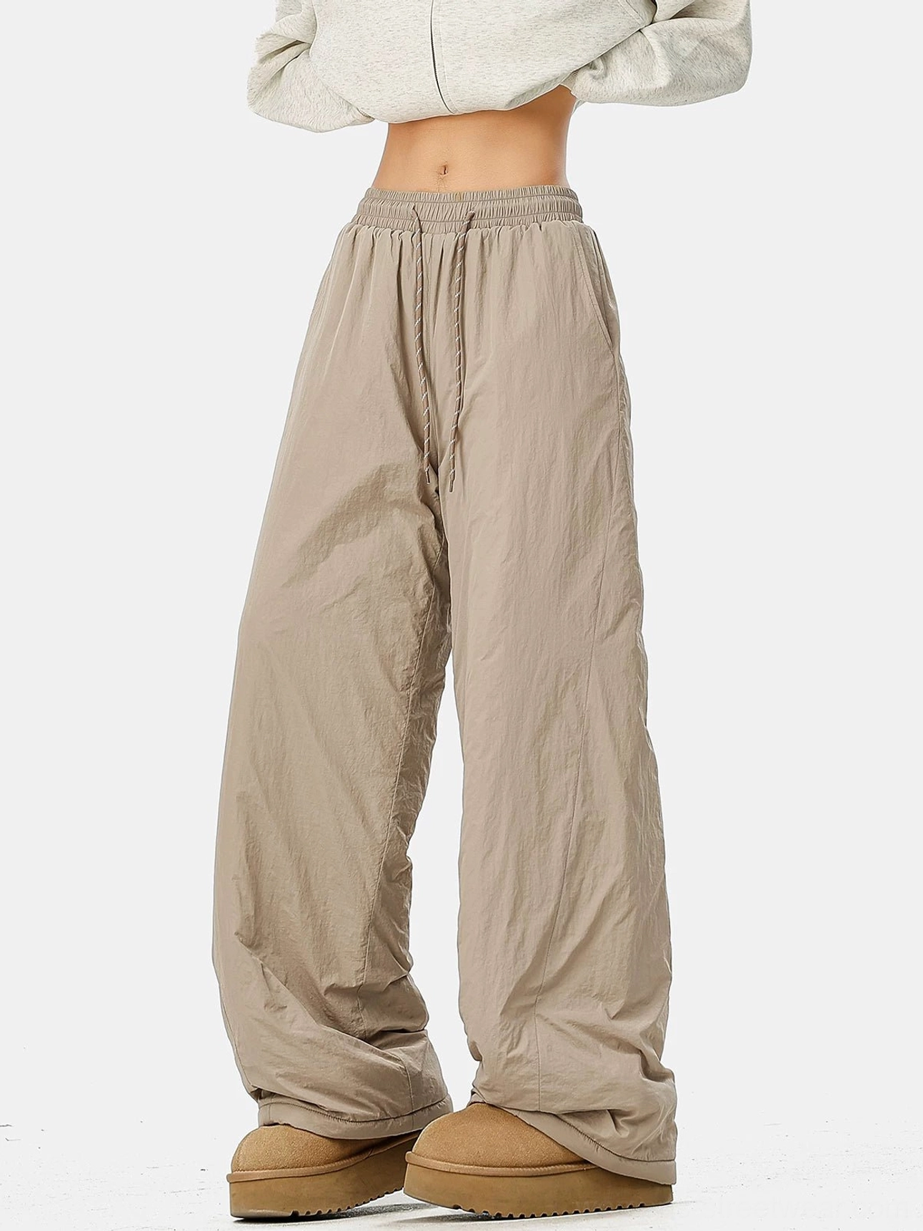 Light khaki convertible wide-leg streetwear pants with crinkled polyester shell, drawstring waist, cropped sweatshirt, and snow boots
