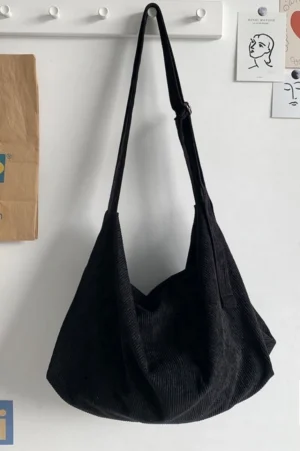 Black corduroy slouchy crossbody bag with soft draped silhouette and long adjustable shoulder strap