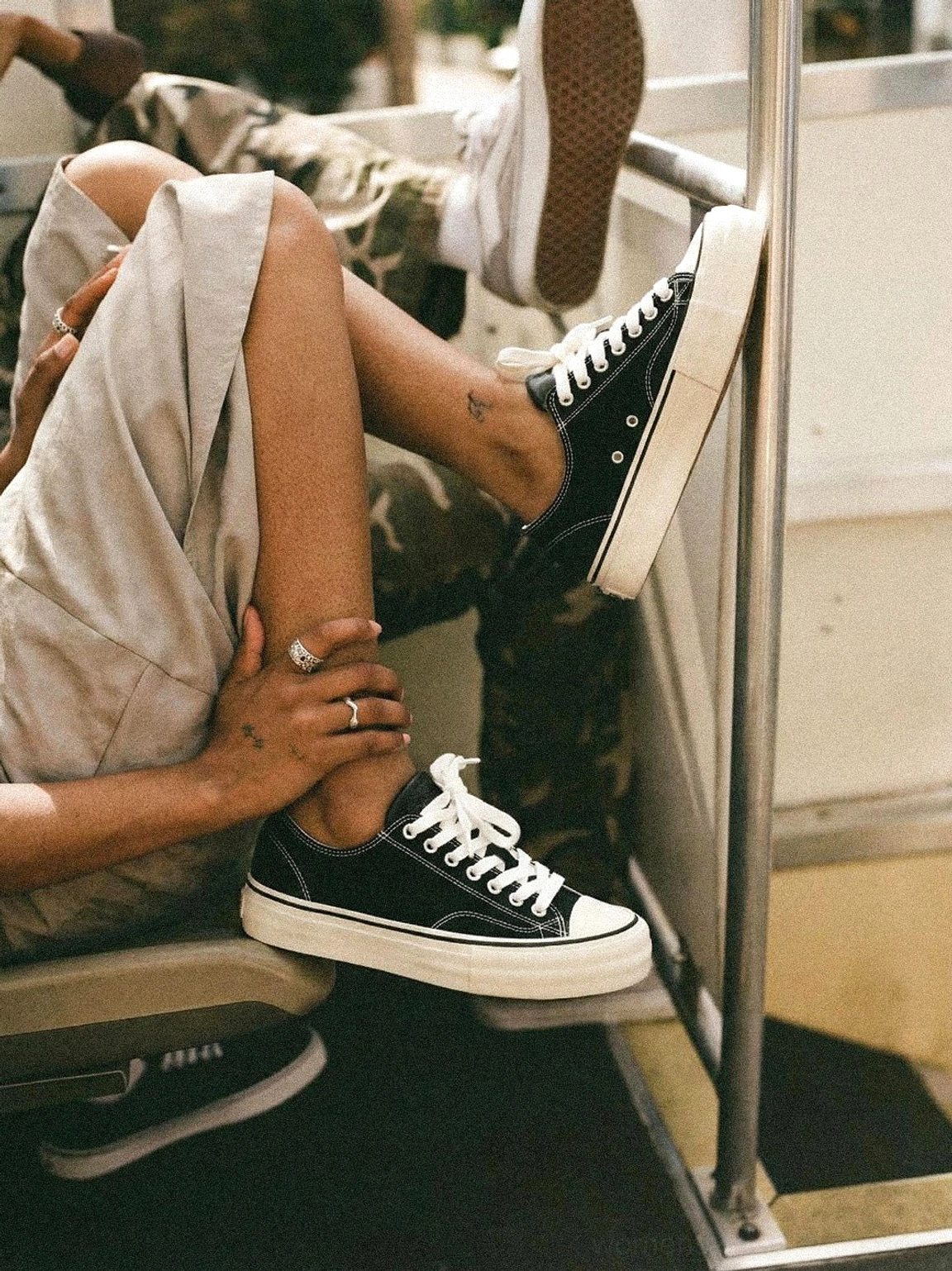 Two people wearing black and white canvas platform sneakers with cork midsole on indoor stairwell, low-angle foot perspective with metal handrail