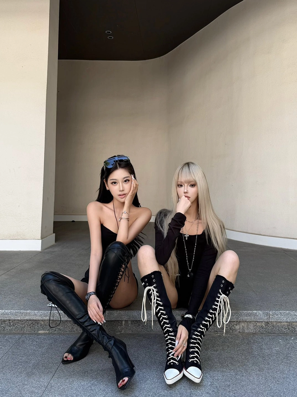 Two models styling black corset lace-up knee-high stiletto boots in a dark Y2K punk streetwear look