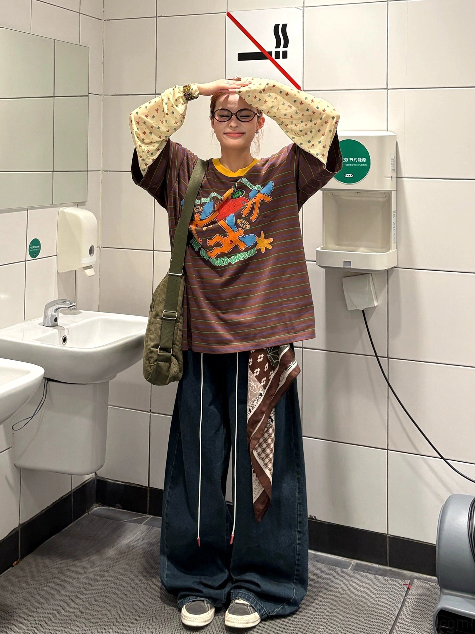 Brown striped fake two-piece graphic long sleeve tee styled with wide leg jeans and crossbody bag, featuring retro cartoon artwork and yellow contrast collar