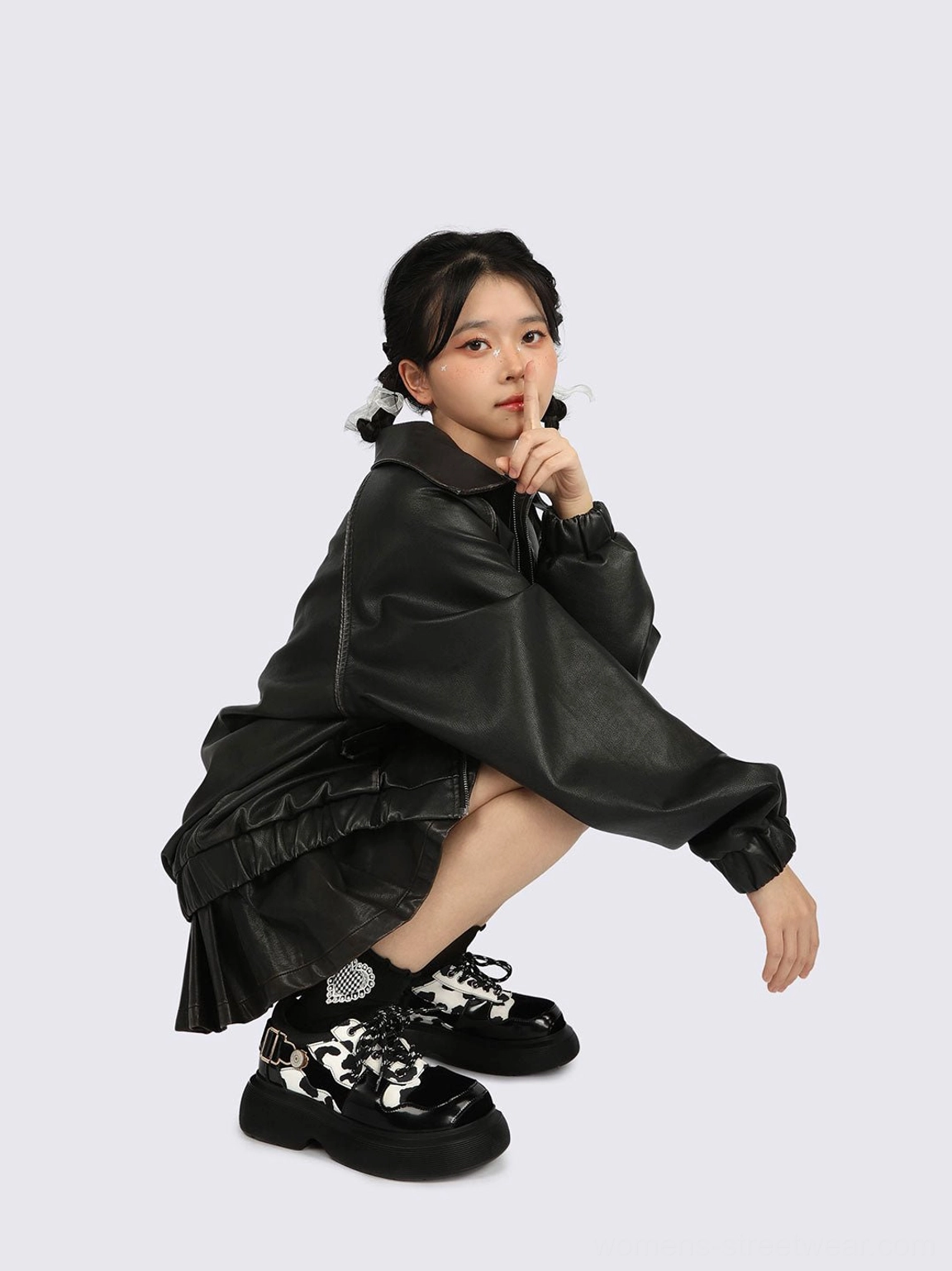 Front low-angle view of cow print platform Mary Jane shoes worn with an all-black leather streetwear outfit