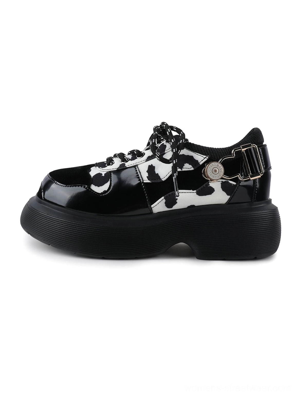Cow print platform Mary Jane shoes with glossy black toe caps, lace-up vamp, side buckle strap, and chunky black platform sole on a light gray background