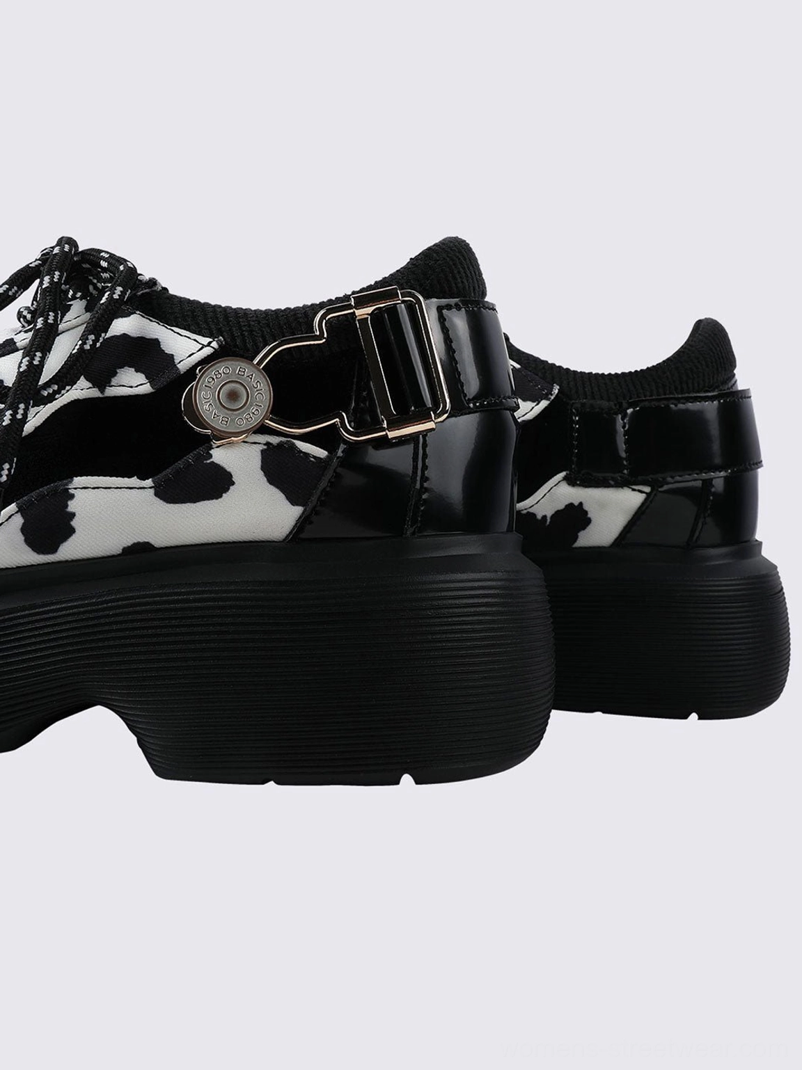 Black and white cow print platform Mary Jane shoes with lace-up vamp, polished toe cap, adjustable buckle, and bold streetwear silhouette