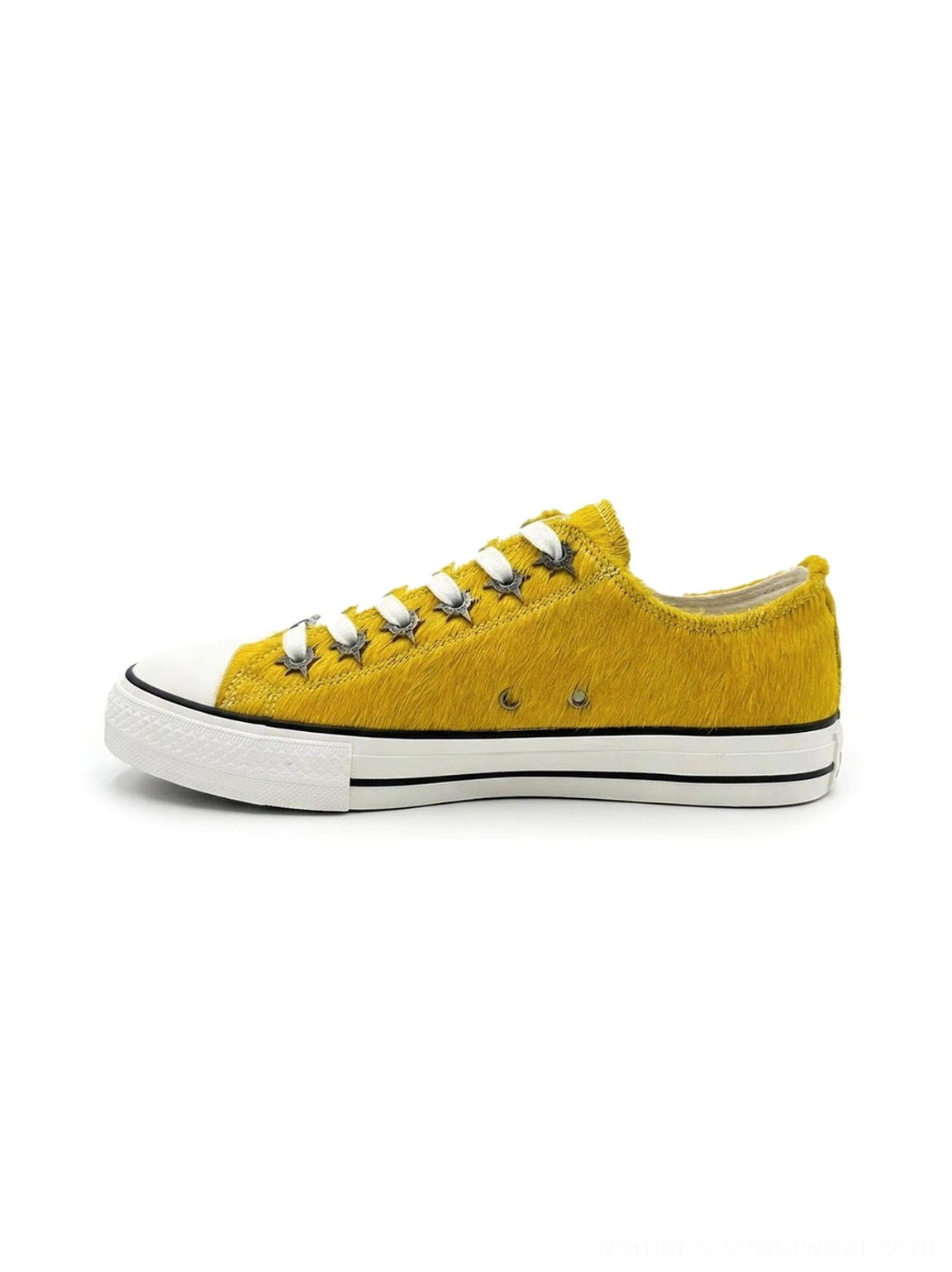 Mustard yellow cowhide low-profile sneakers with textured leather upper, white rubber toe cap, black side stripe, and flat vulcanized sole shown from the left side