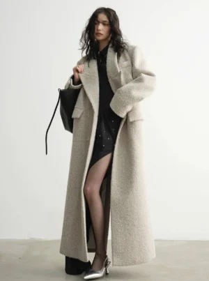 Creamy beige oversized floor-length wool coat styled with sheer black stockings and silver heels for an elegant streetwear look