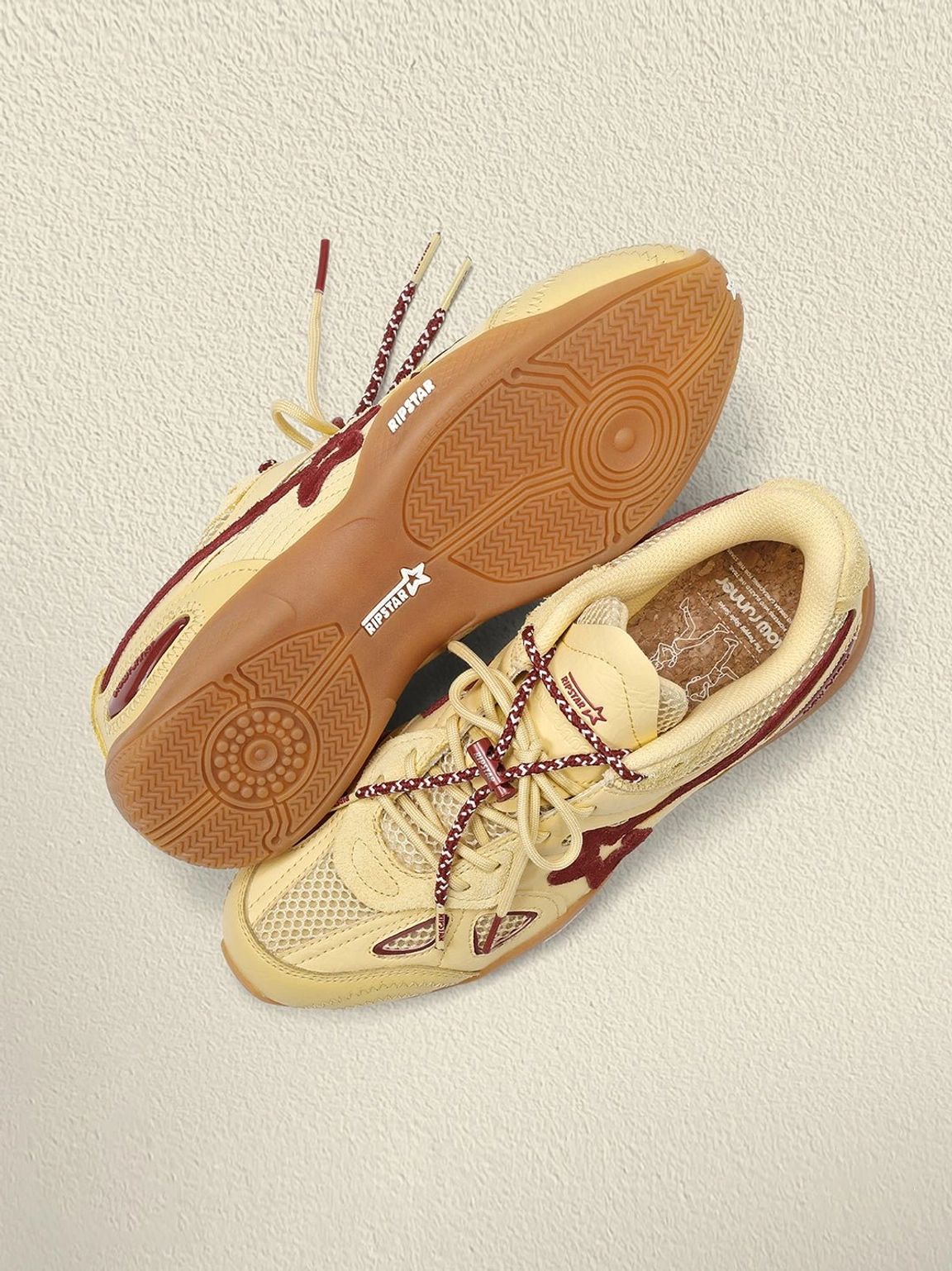 Textured gum rubber outsoles of cream burgundy star retro running sneakers with heel star branding