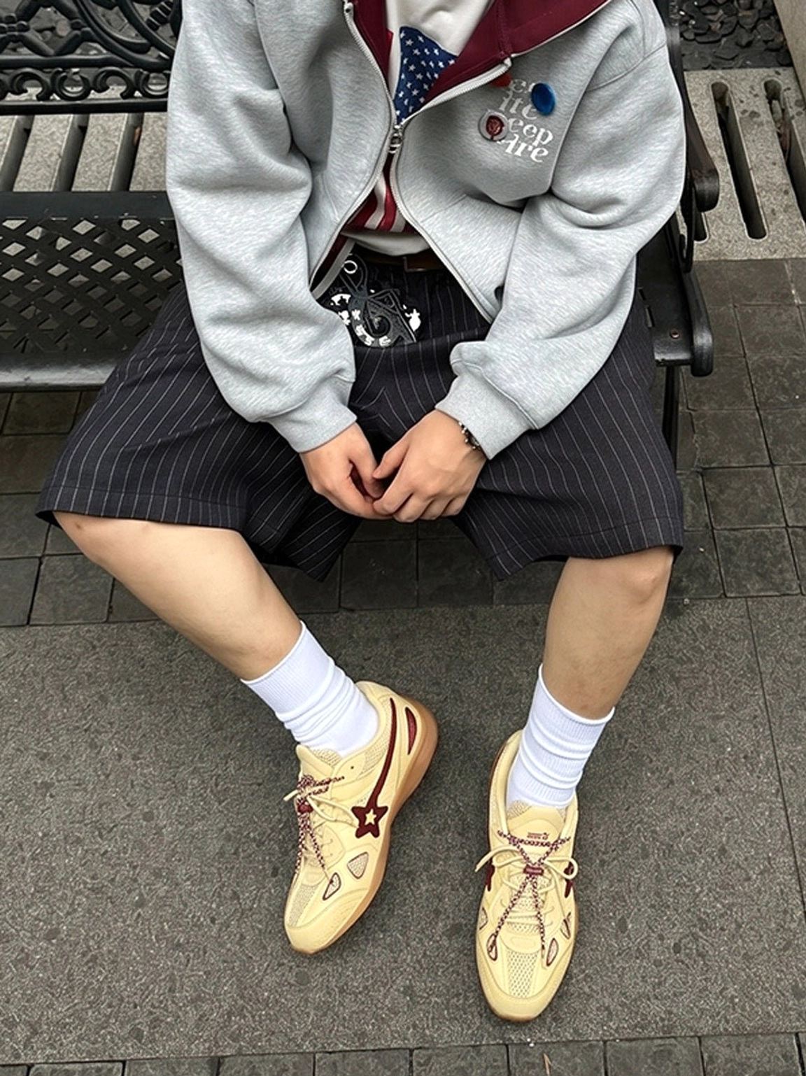 Male model styling cream burgundy star retro running sneakers with crew socks, shorts and relaxed streetwear layers