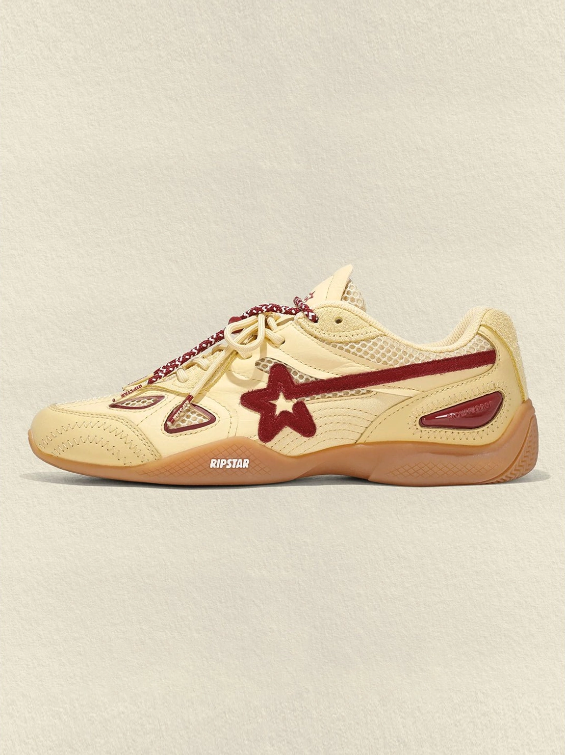 Close side view of cream burgundy star retro running sneakers showing star logo, mesh ventilation and toe branding