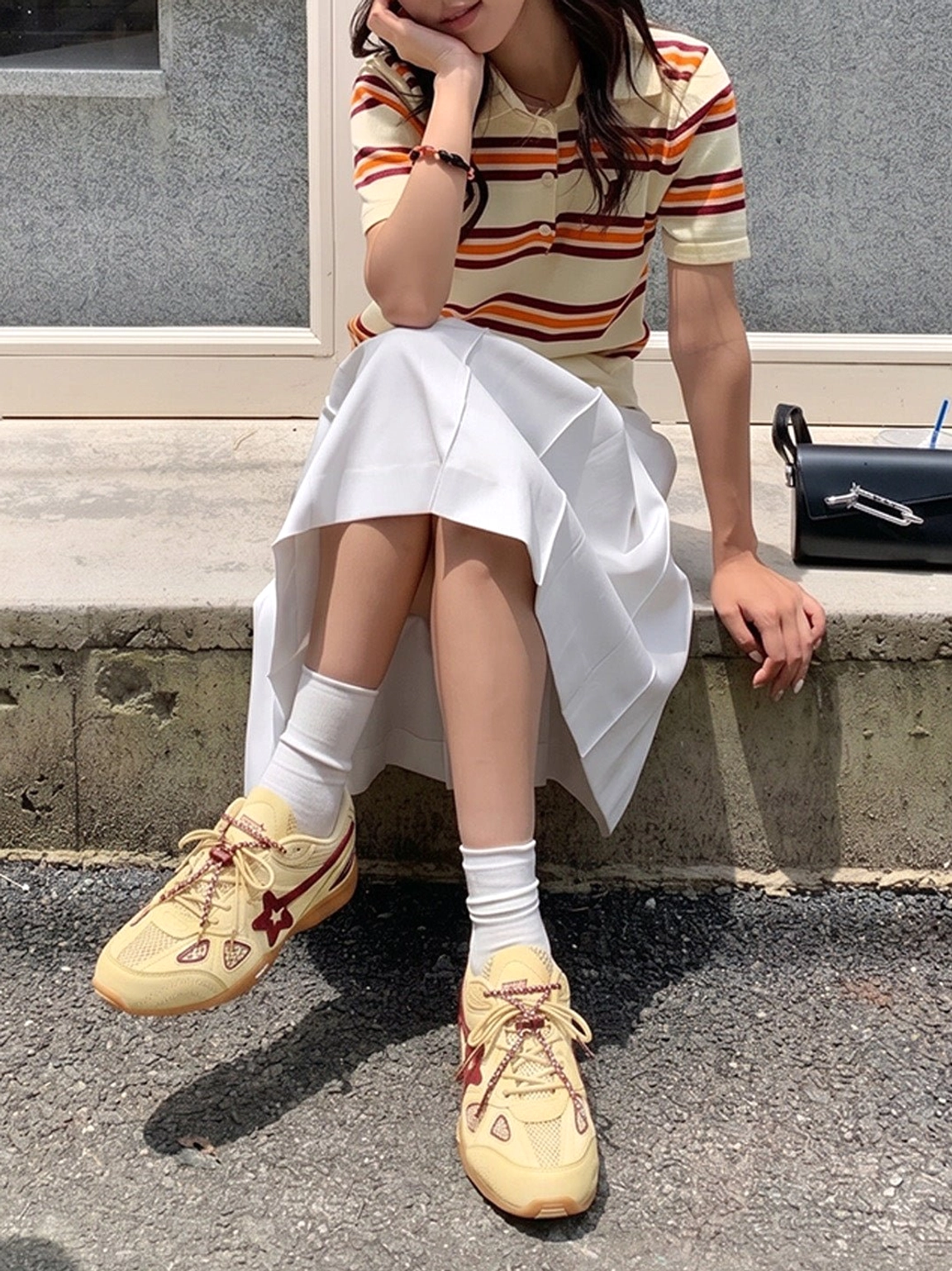 Female model wearing cream burgundy star retro running sneakers with white socks, striped polo and midi skirt
