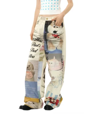 Front three quarter view of cream cartoon graphic print baggy jeans with colorful dog illustrations cursive typography and wide leg Korean streetwear styling