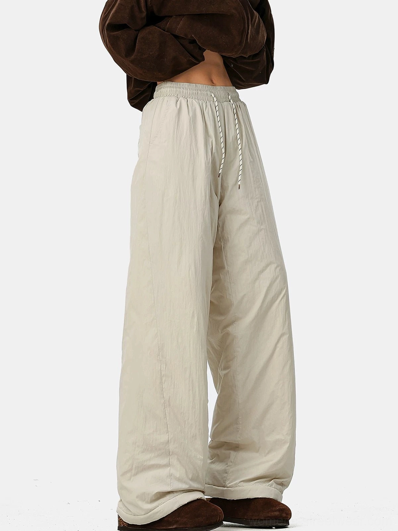 Cream convertible fleece-lined wide-leg pants with relaxed crinkled fabric, drawstring waist, cropped top, and winter boots