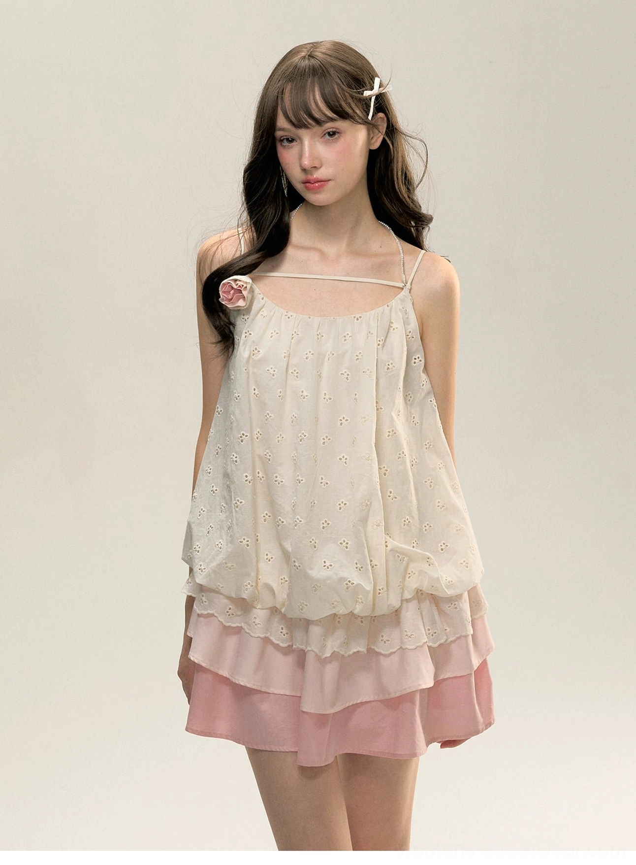Three-quarter view of feminine cream embroidered bodice and pink layered ruffle mini dress with fabric flower shoulder strap detail