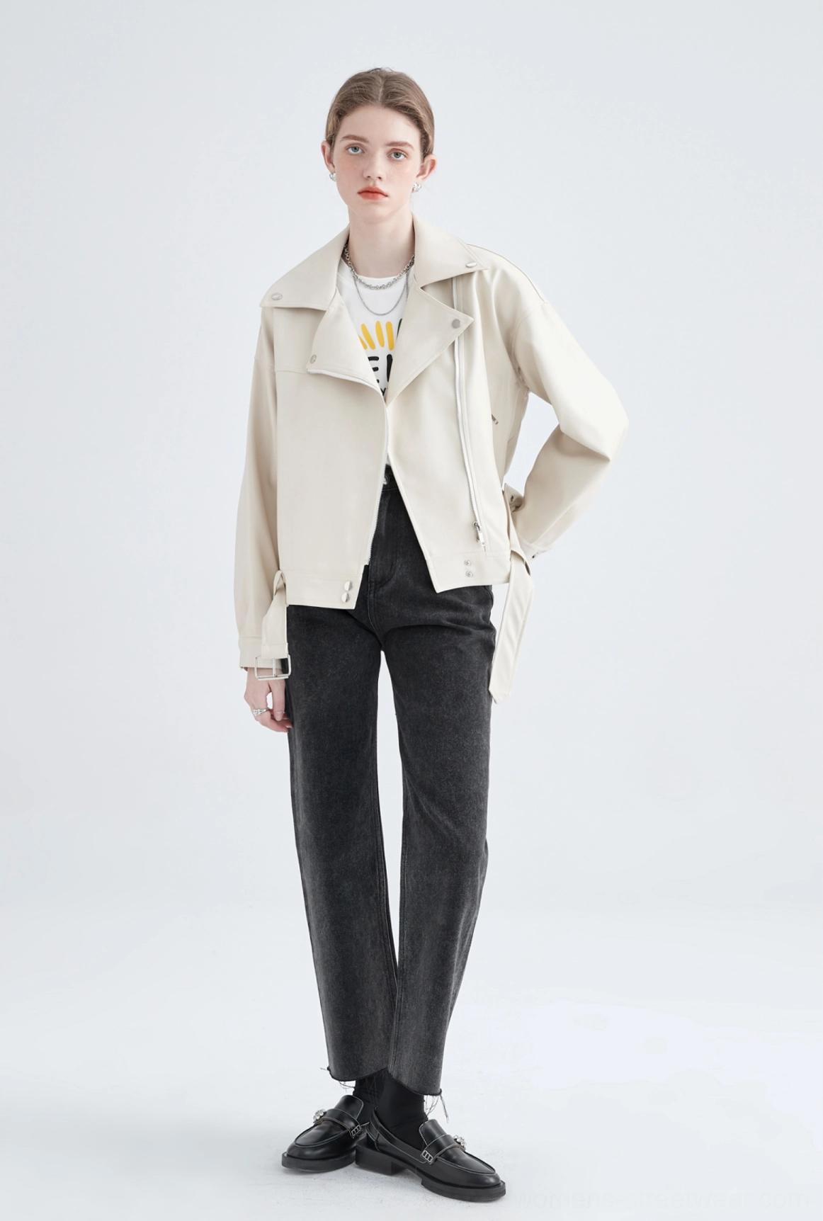 Full body front view of cream cropped faux leather biker jacket styled with black jeans and loafers