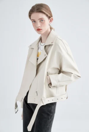 Side three-quarter view of cream faux leather moto jacket with relaxed drop shoulders and adjustable hem belt