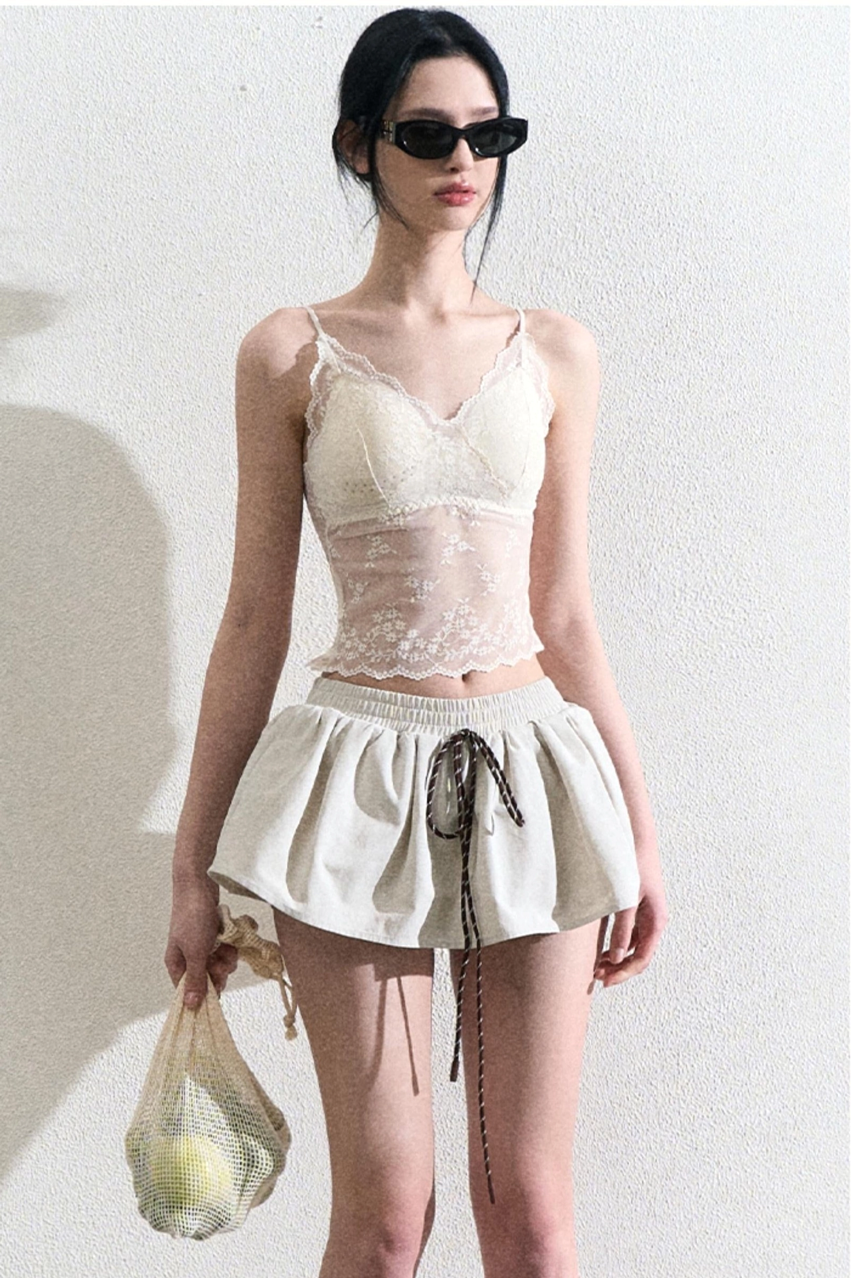 Front outfit view featuring a cream fitted lace camisole top and high waisted drawstring mini skirt