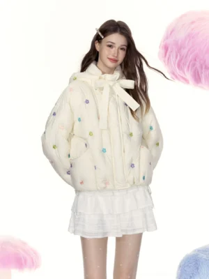 Cream floral embroidered cropped puffer jacket shown from a right oblique angle with colorful flower details, tie-up collar, side pockets, and relaxed Y2K streetwear styling