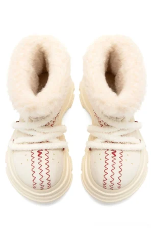 Pair of cream furry platform snow boots front view showing plush inner lining red toe stitching and chunky lug soles