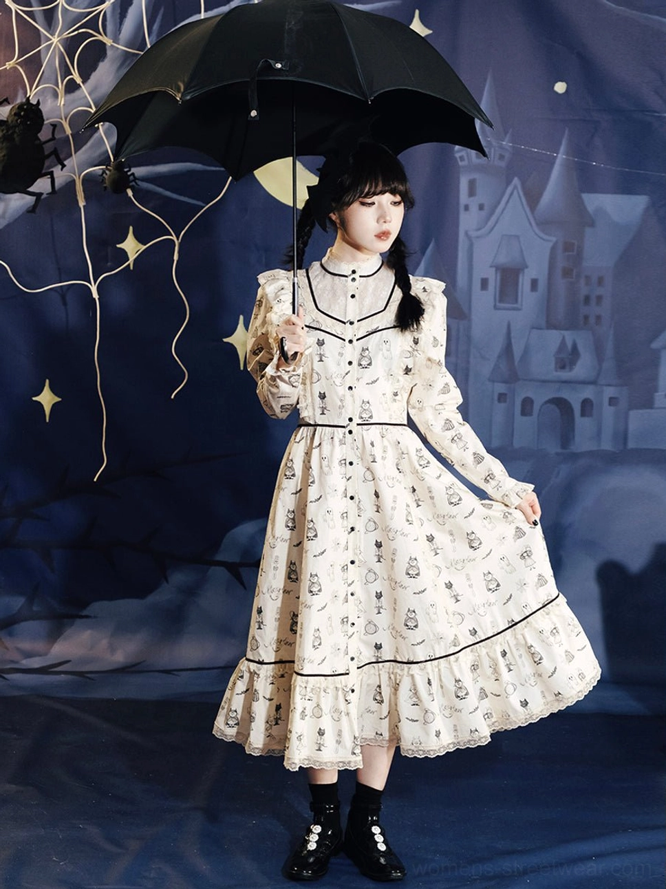 Front full-body view of cream ghost print Victorian gothic Lolita midi dress with black lace trims and velvet ribbons in a Halloween castle setting