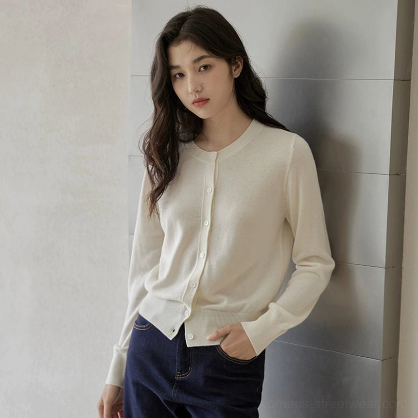 Cream ivory women's slim long-sleeve crew neck button cardigan shown with one hand in a jeans pocket