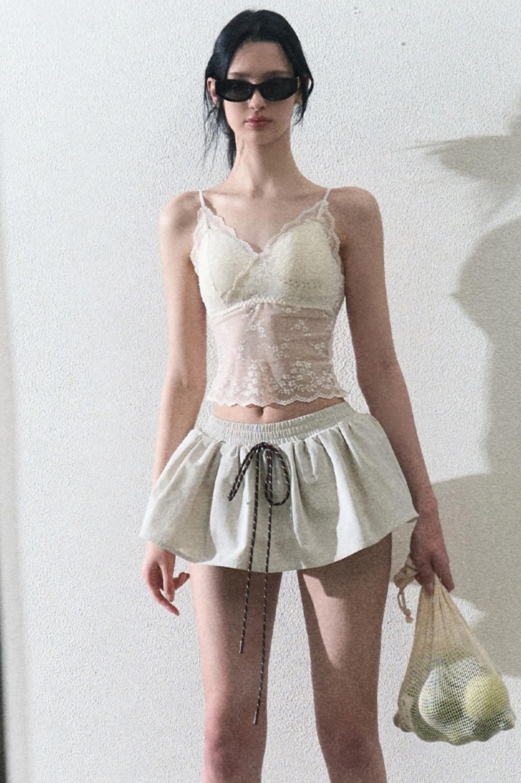 Cream lace camisole top with structured lace bust and sheer torso panel styled in a monochrome outfit