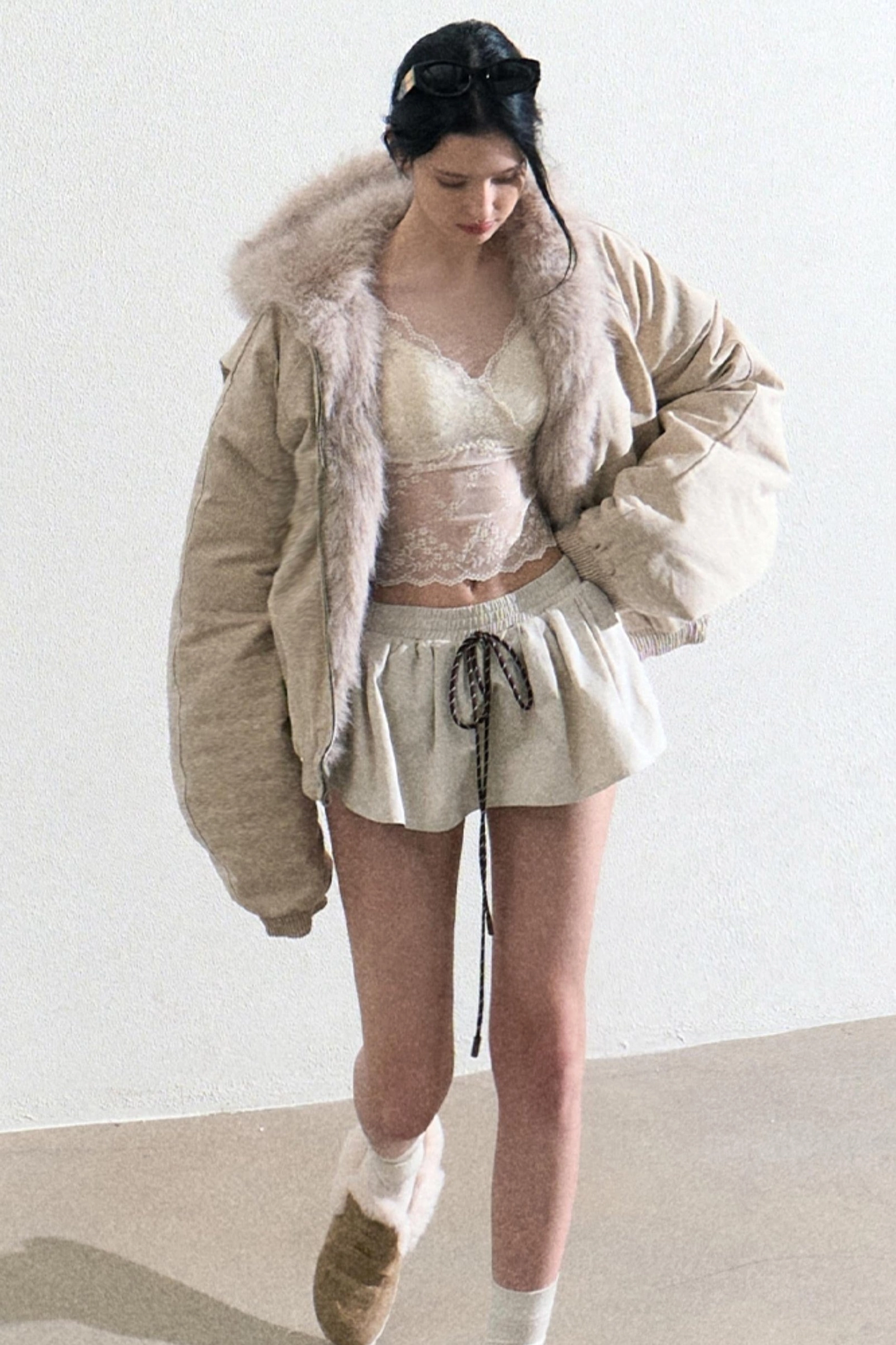 Three quarter view of a cream lace sheer camisole layered under a faux fur coat for winter streetwear