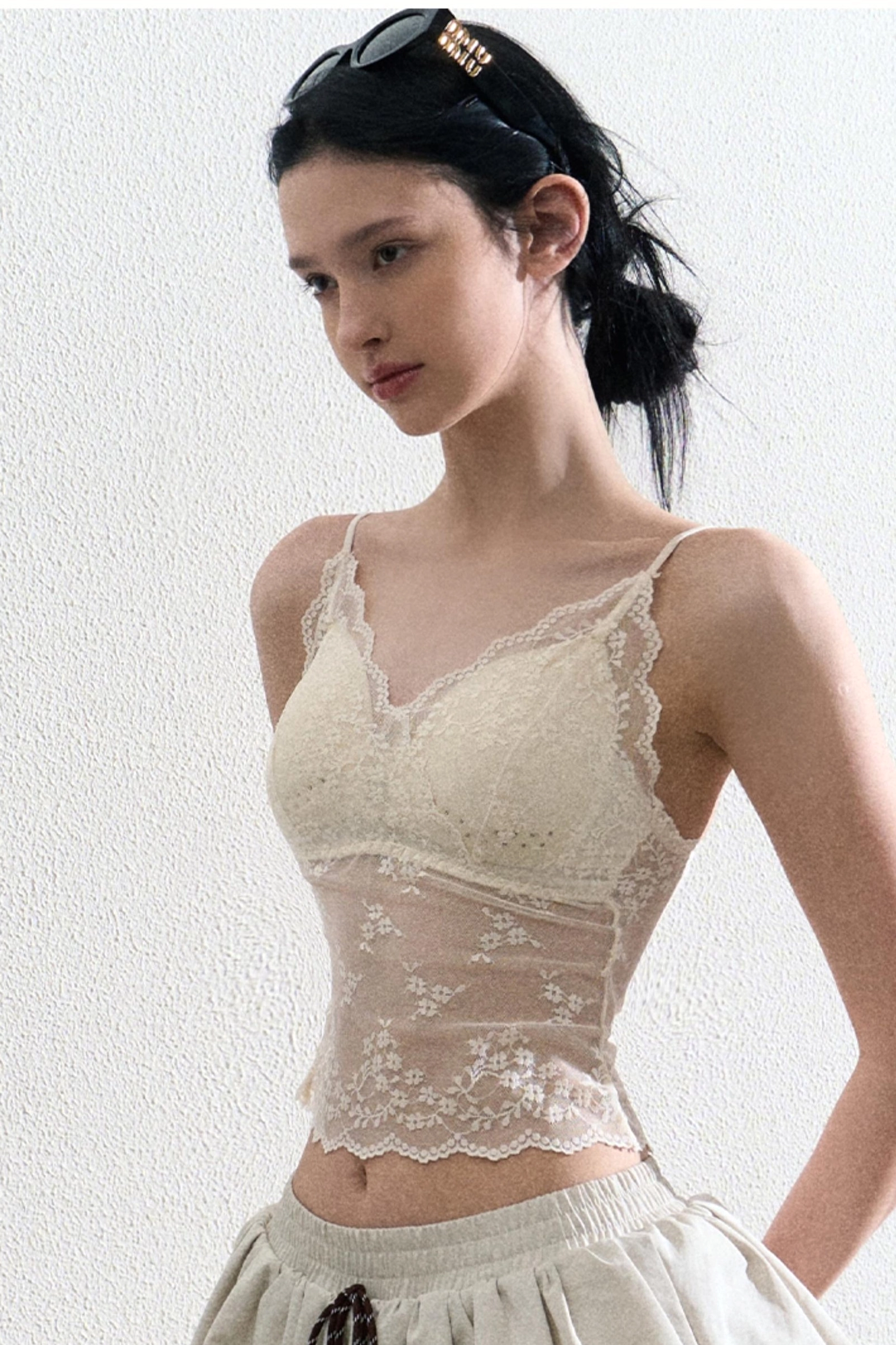 Three quarter view of a fitted cream lace sheer camisole with floral mesh bodice and delicate V neckline