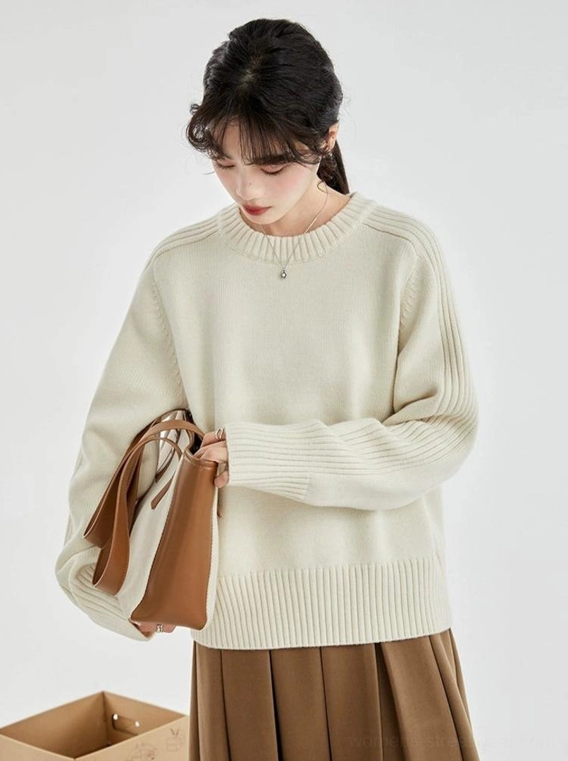 Side three-quarter view of a cream long-sleeve ribbed crewneck sweater showing the relaxed straight silhouette and neat hem