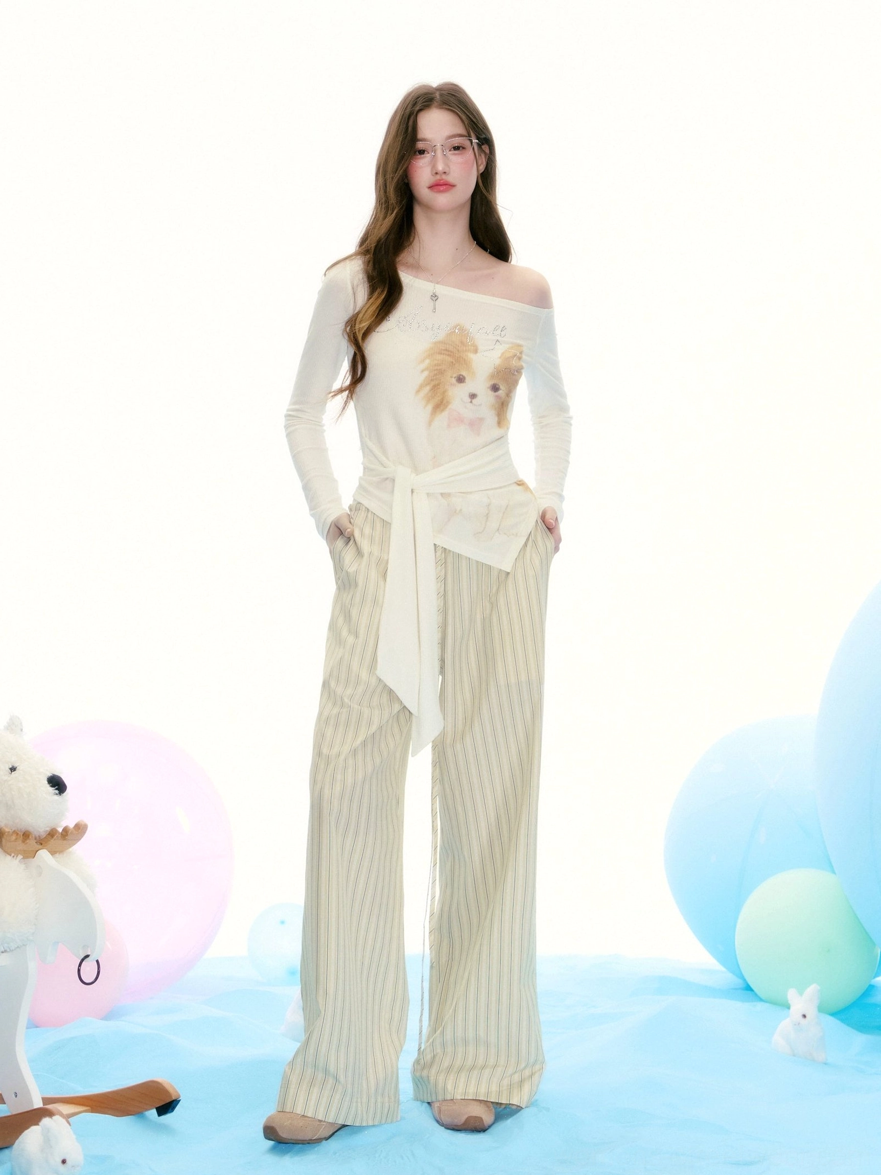 Front view of cream Papillon dog graphic off-shoulder tie-waist top styled with striped wide-leg trousers