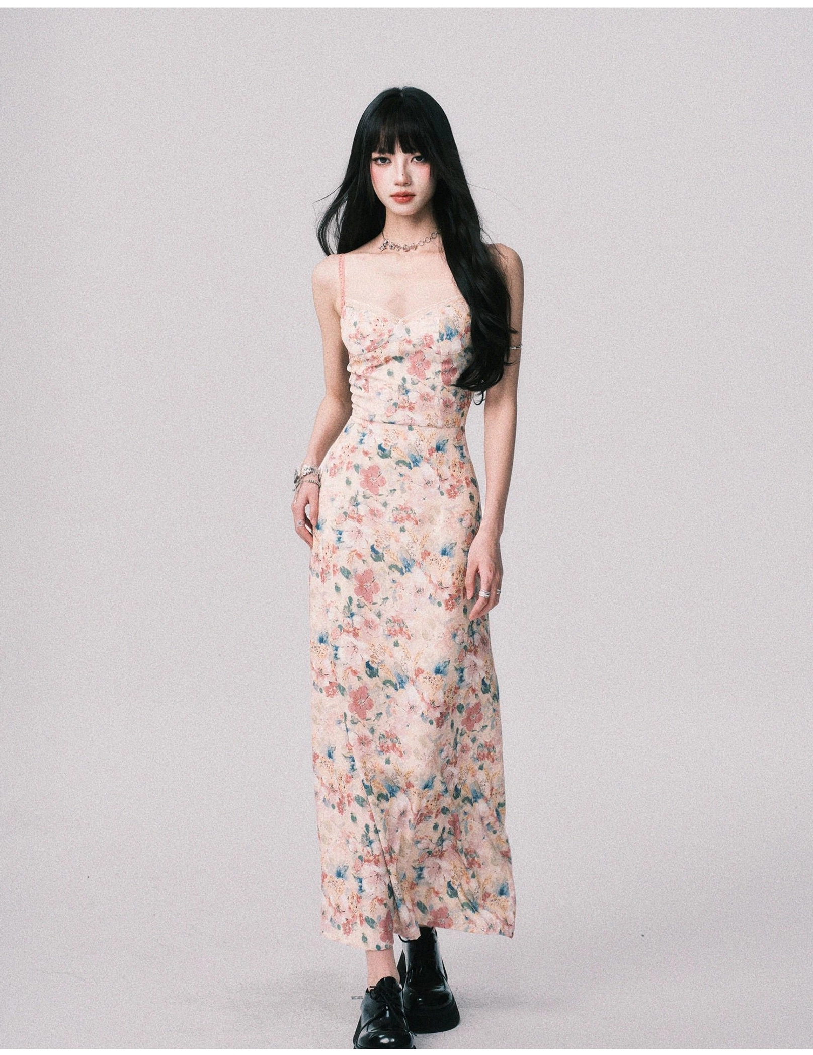 Three quarter view of a cream based floral slip maxi dress with fitted silhouette, spaghetti straps, watercolor print, and delicate bracelet styling