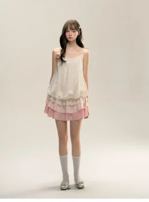 Front view of cream and pink floral tiered ruffle mini slip dress with embroidered bodice, spaghetti straps, fabric flower detail, white socks, and silver flats