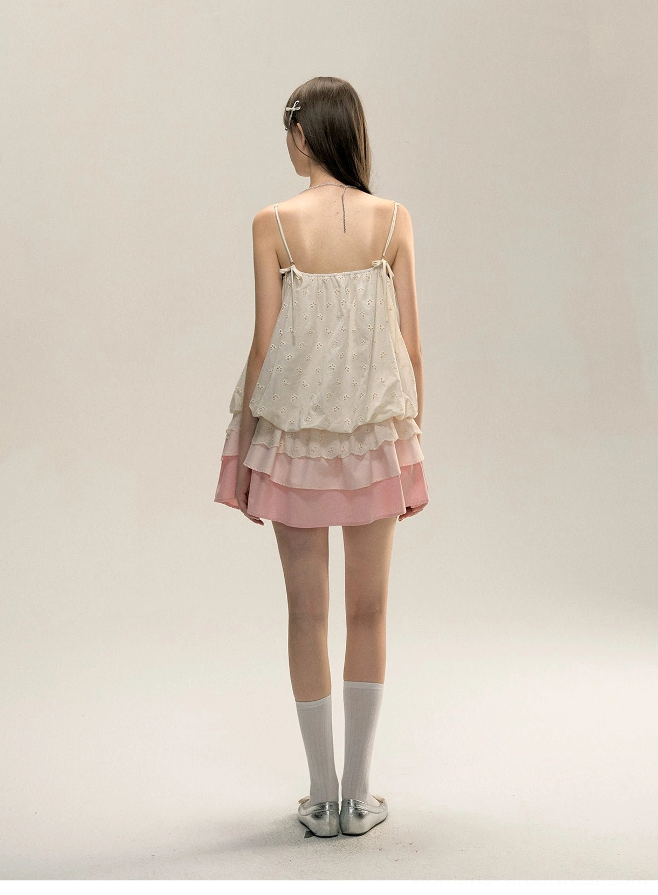 Back view of cream embroidered open-back mini slip dress with thin spaghetti straps and pink tiered ruffle skirt