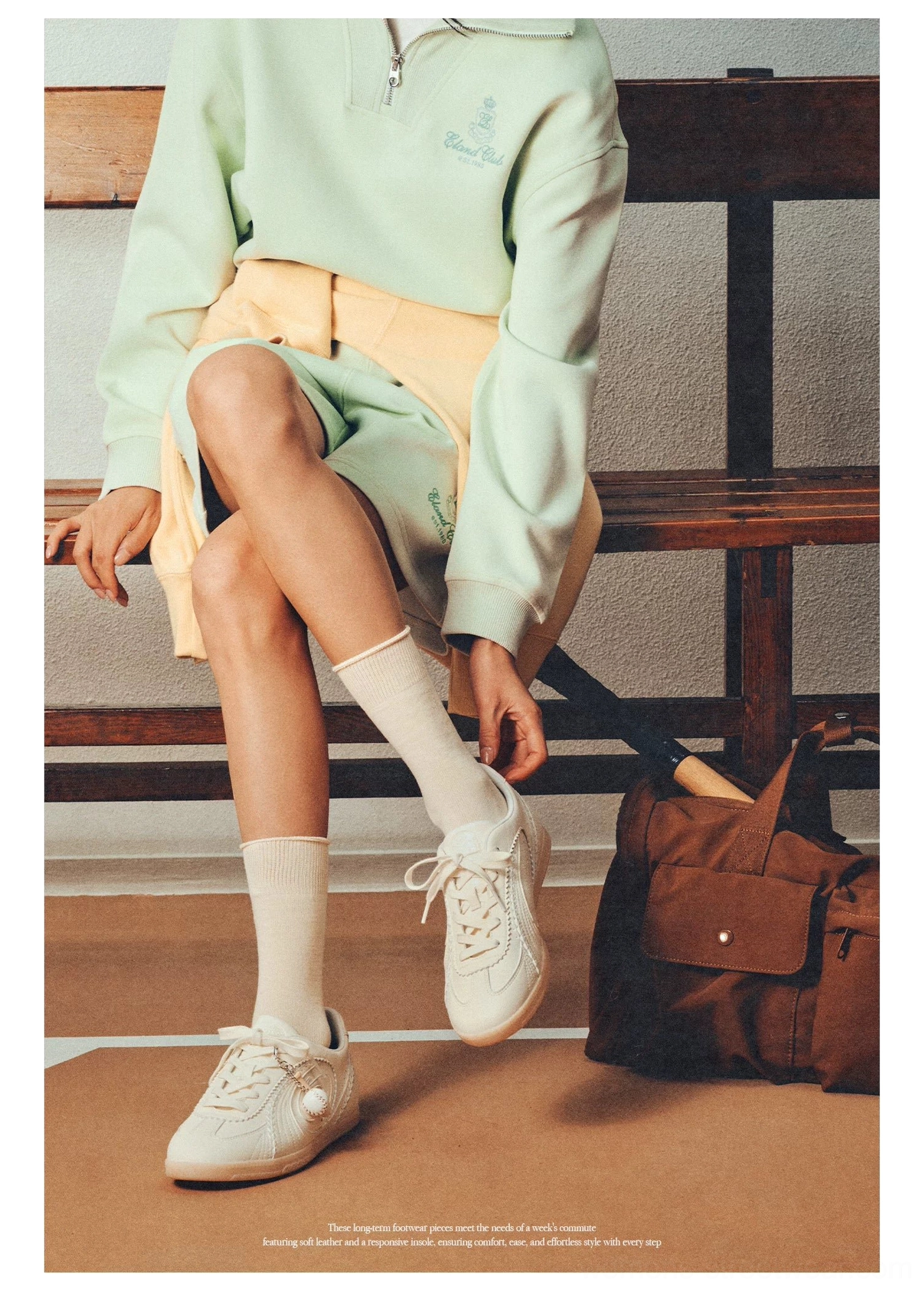 Cream retro training sneakers worn with light green casual outfit on an indoor sports court