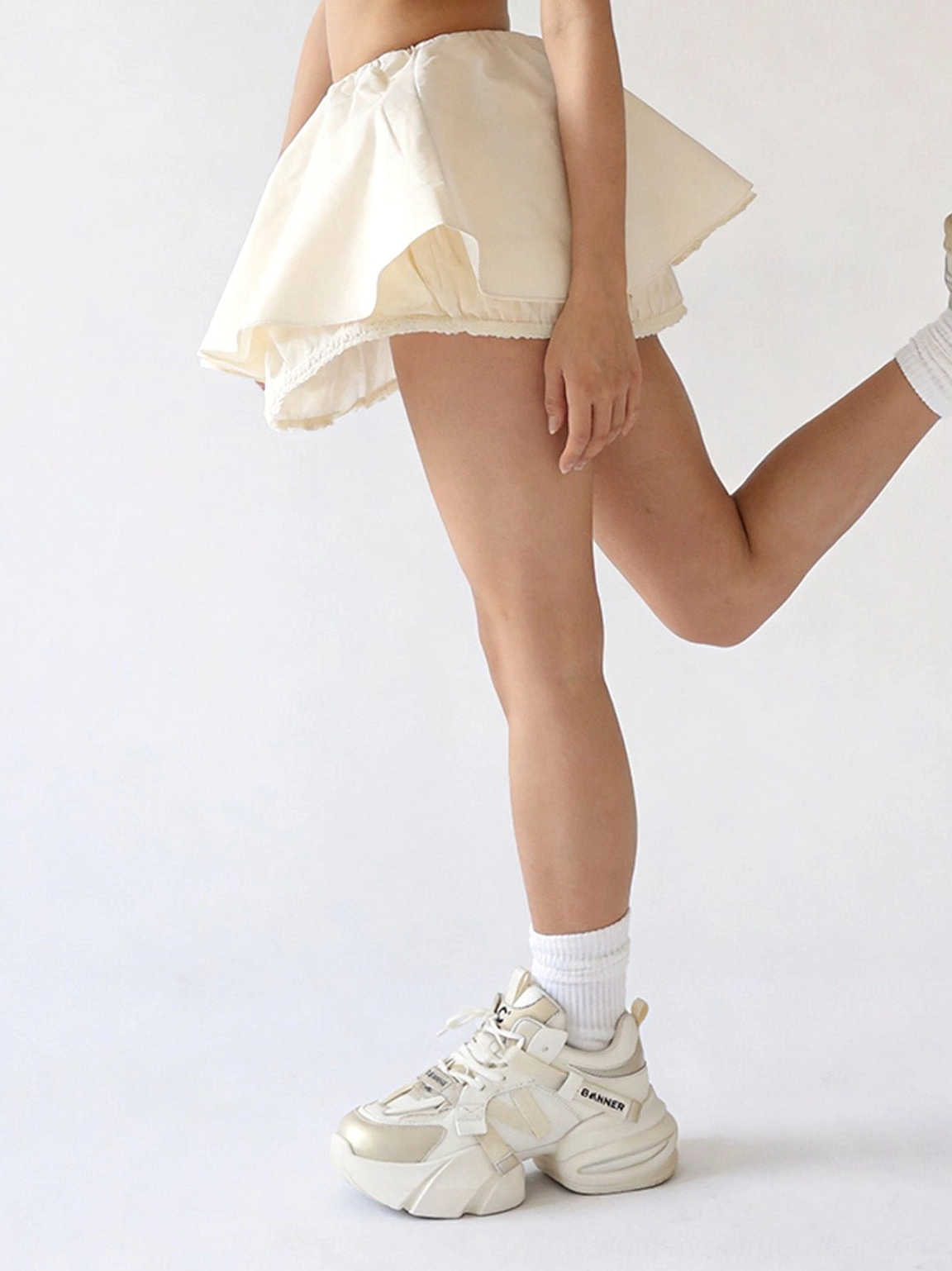 Side profile of cream white chunky dad sneakers showing the raised sculpted sole and low-top silhouette
