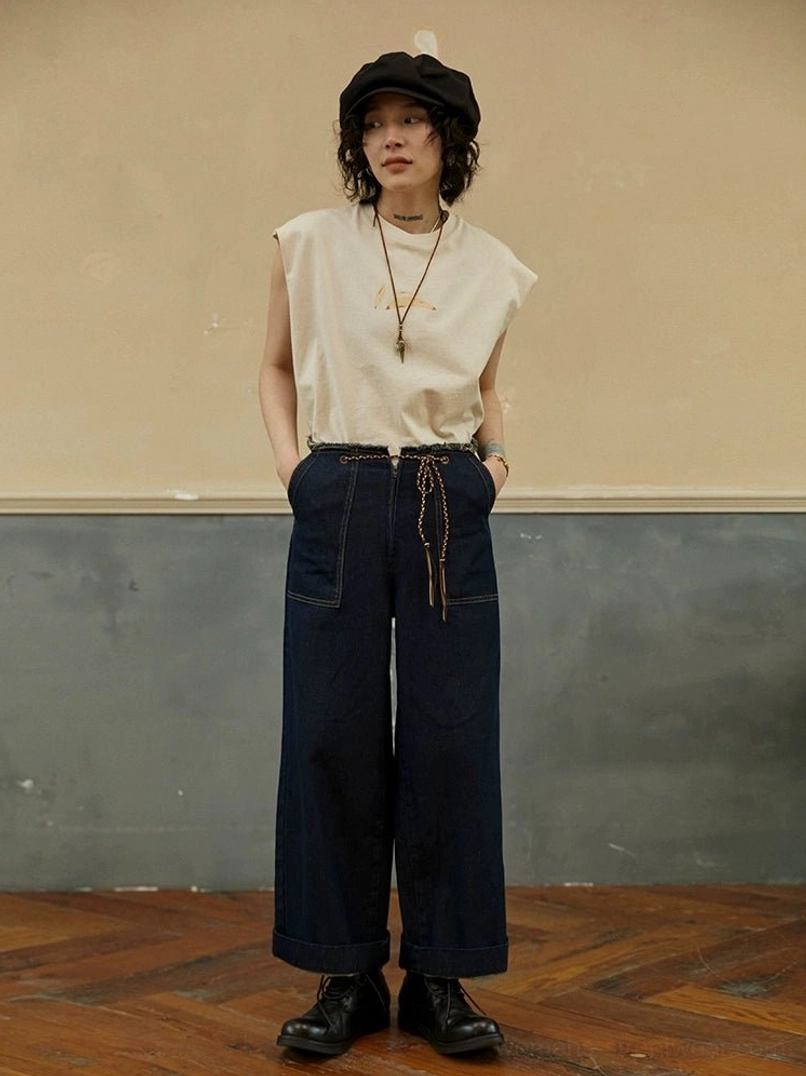 Cream White minimalist sleeveless tee with subtle chest graphic styled with wide-leg jeans, beret, and leather boots