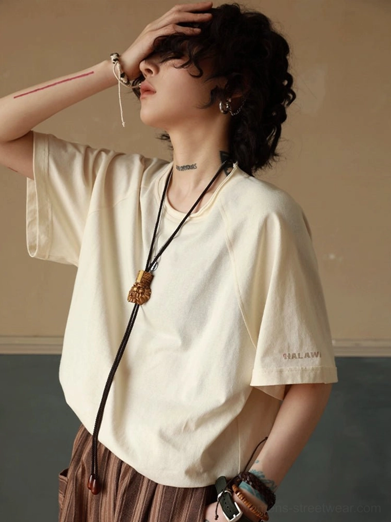 Cream white raglan sleeve t-shirt side view showcasing shoulder seam construction and raw edge details with bohemian lanyard accessory