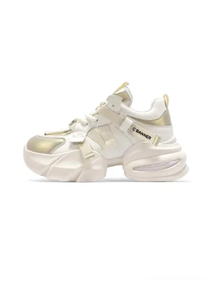 Cream white stitched panel chunky dad sneakers with champagne gold accents and thick sculpted platform sole in three-quarter view