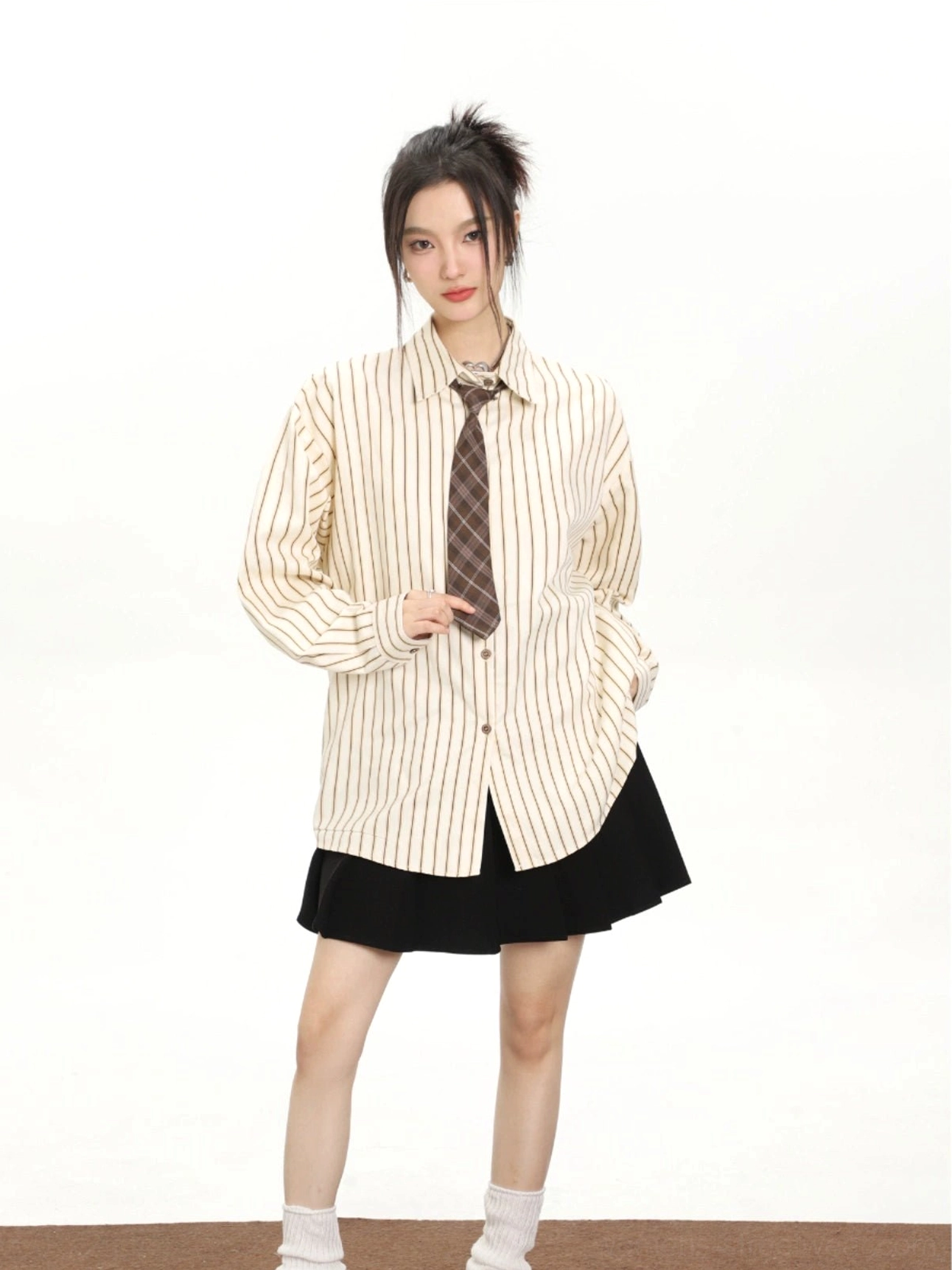 Cream white vertical striped long sleeve shirt styled with a brown plaid tie and black pleated mini skirt