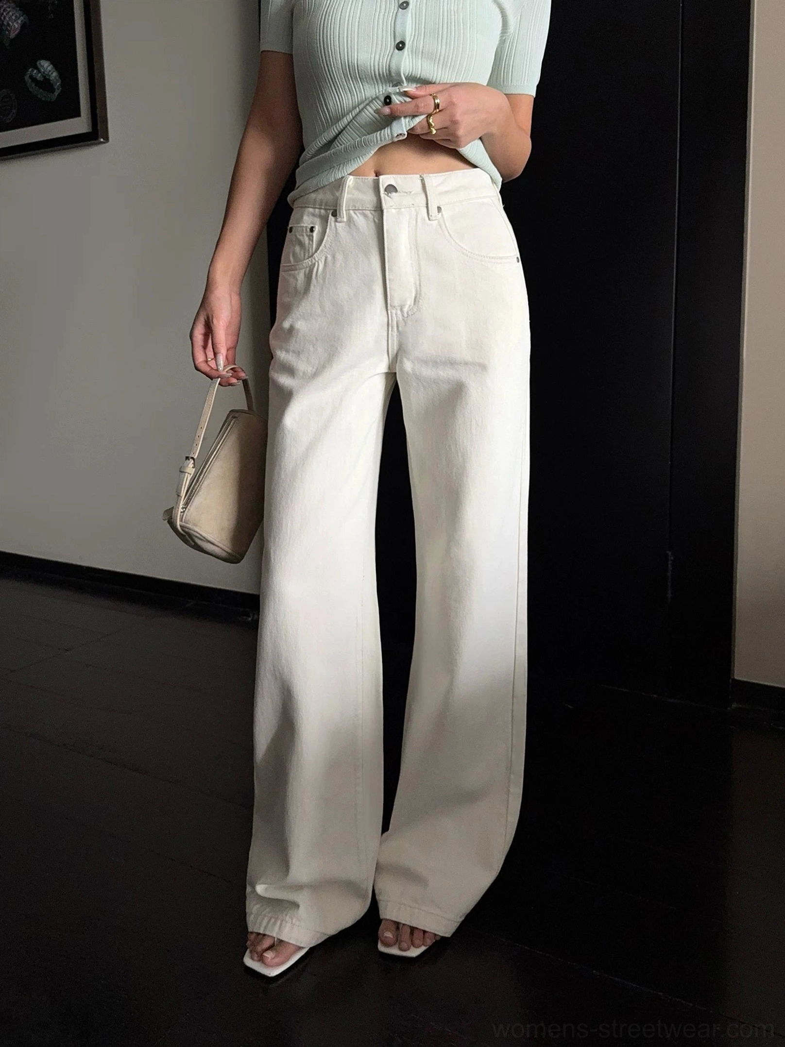 Front low-angle full-length view of cream wide-leg denim pants with a mint cropped knit top beige handbag and open-toe mules